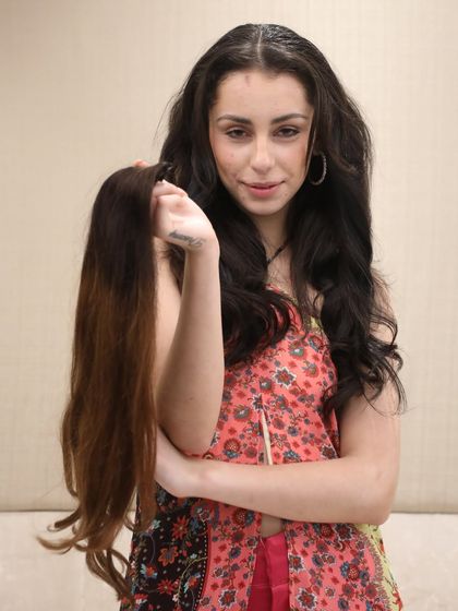 This model is holding a straight, ombre-colored hair extension piece. It's a great way to add length and a subtle color gradient to your hair for a stylish look.