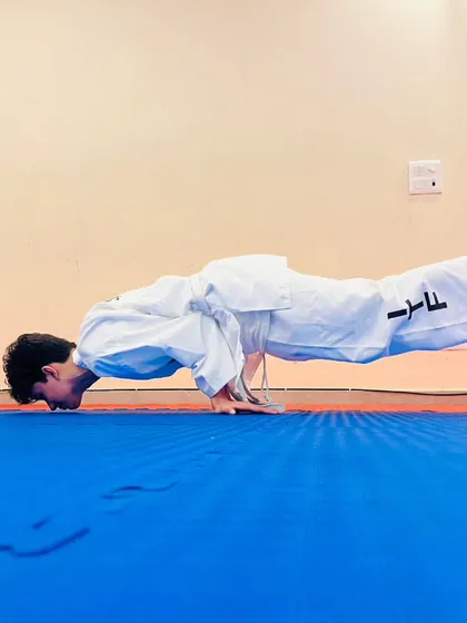 A student demonstrates incredible core strength and balance by holding a planche push up. This level of physical conditioning is a product of intense and consistent training.