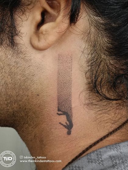 A minimalist dotwork tattoo behind the ear depicting a figure falling into a beam of light. This abstract piece, titled "The Fall," uses stippling to create a gradient effect, telling a story of surrender or descent.