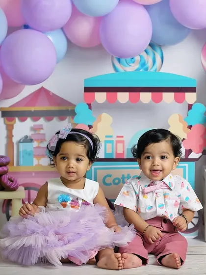 A sweet candyland theme for a set of one-year-old twins. The pastel colors, cotton candy stand, and donut props create a delightful and whimsical scene.