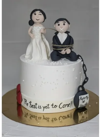 A playful cake for a bride and groom to be. This choco-vanilla cake features funny, handmade fondant toppers showing the bride has "captured" her groom.