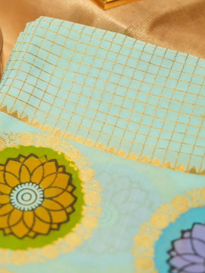 A close-up of the checked pattern and floral motifs on the blue Mysore silk saree.