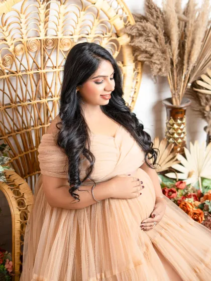 A bohemian dream. Seated in a wicker peacock chair, this mother-to-be glows in a beautiful nude-colored tulle gown, creating a warm, rustic, and stylish portrait.
