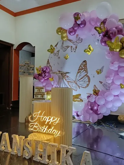 Another view of the home-based butterfly party, showing the arrangement of props and the purple and gold balloon garland.