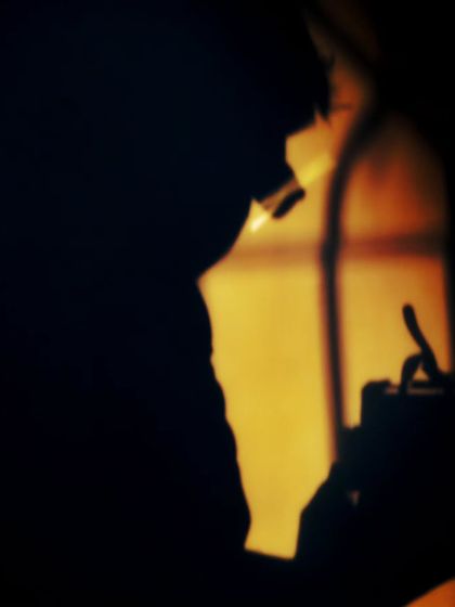 A self-portrait silhouette captured using the light from my bedroom window. I love how the warm light creates a dramatic shadow and even catches the glint on my glasses.