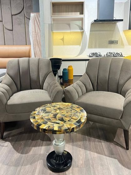 A pair of our versatile armchairs in a neutral grey fabric, paired with a side table featuring a horn inlay top. This shows how we mix and match our custom pieces to create unique looks.