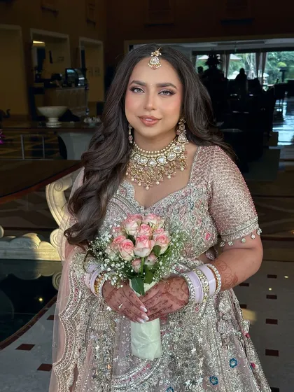 A fresh day-bride all the way from Dubai for her sundowner wedding in Jaipur. Her makeup is soft and radiant, paired with a simple bouquet of pink and white roses for a touch of romance.