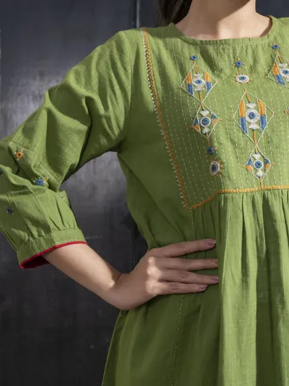 This detail shot of the Paheli green dress highlights the embroidery on the sleeve and the gathers at the waist, creating a flattering and comfortable silhouette.