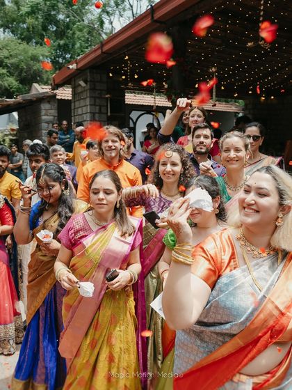 Guests joyfully shower the couple with flower petals, their faces full of happiness and blessings.