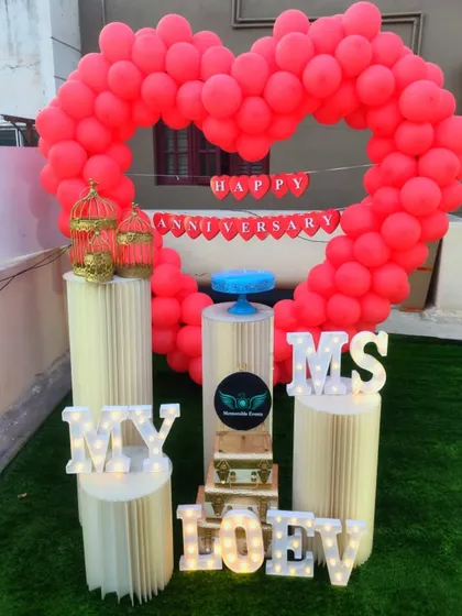 Perfect for an anniversary, this romantic decoration features a large heart-shaped balloon arch in bright red. The setup is personalized with 'My Love' marquee letters and elegant plinths for a memorable surprise.