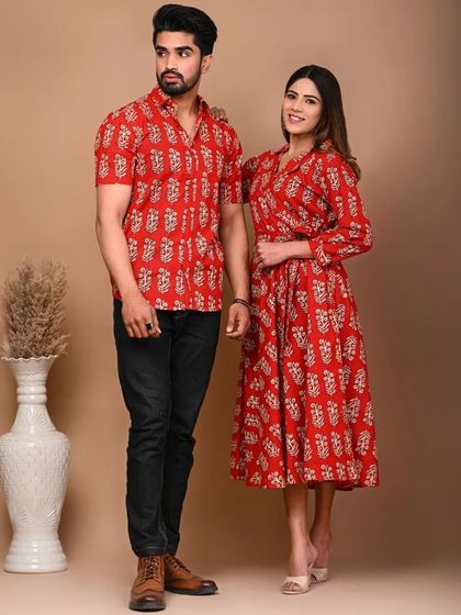 A vibrant red Jaipuri print couple set. The woman's wrap-style kurti dress and the man's casual half-sleeve shirt are crafted from pure, breathable cotton for a comfortable and eye-catching coordinated look.