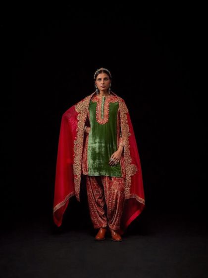 A powerful, full-length shot of a model in a green and red velvet outfit from Debyani & Co.
