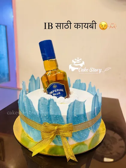 'IB saathi kaybi!' A fun cake for a whiskey lover, designed to look like a bottle of Imperial Blue chilling on ice. The 'ice' is created with blue and white frosting effects.