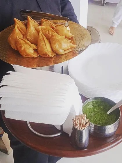 A tray of hot samosas served with fresh green chutney, perfect for a post-hawan snack. I cater to all religious and cultural events with appropriate menu options.