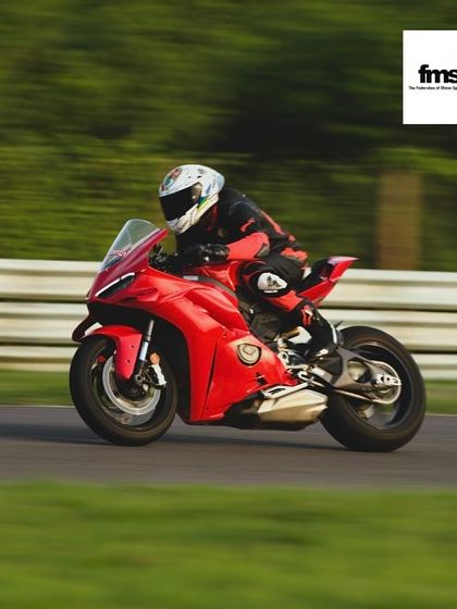 A rider on a red Ducati, tucked in and focused on the track ahead. Learning to be comfortable at high speeds is a major confidence booster.