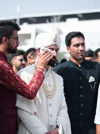 A friend wiping a tear from the groom's eye. A testament to the deep emotions of a wedding day.