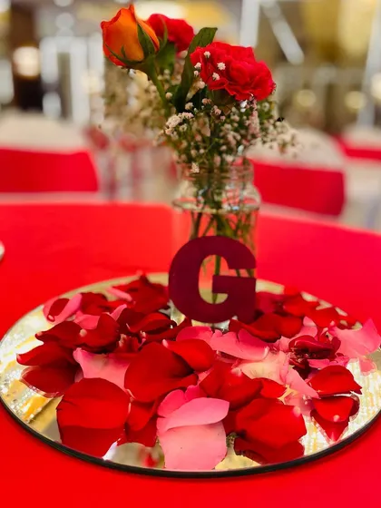 A simple yet elegant centerpiece for a red-themed event. I used a mirror plate, scattered rose petals, and a custom initial to personalize the table setting.