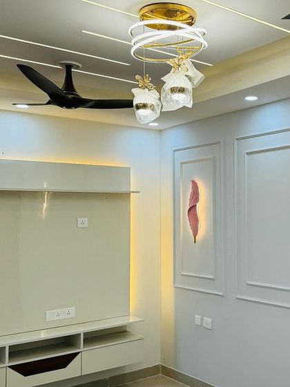 Another angle of the elegant living room, showing the clean lines of the TV unit and the beautiful false ceiling with modern lighting.