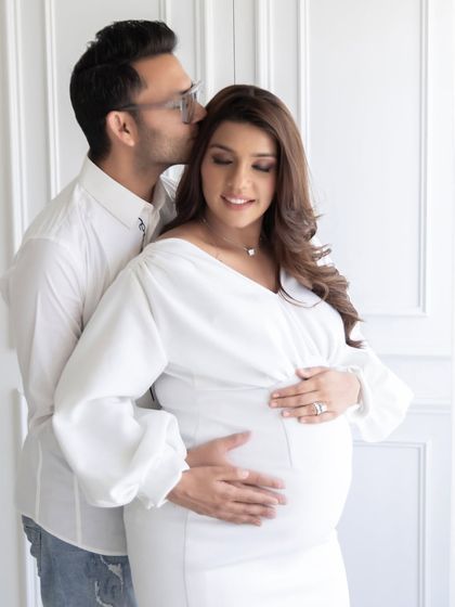 An intimate and tender portrait of an expecting couple. The soft lighting from the large studio windows creates a gentle and romantic mood, ideal for maternity photography.