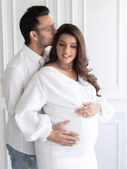 An intimate and tender portrait of an expecting couple. The soft lighting from the large studio windows creates a gentle and romantic mood, ideal for maternity photography.