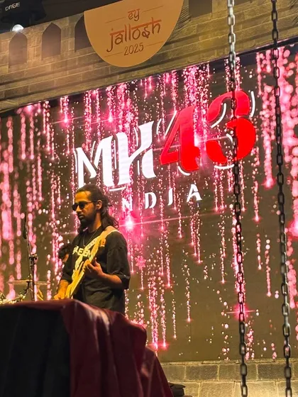 Our guitarist on stage against a backdrop of our logo and dazzling pink lights.