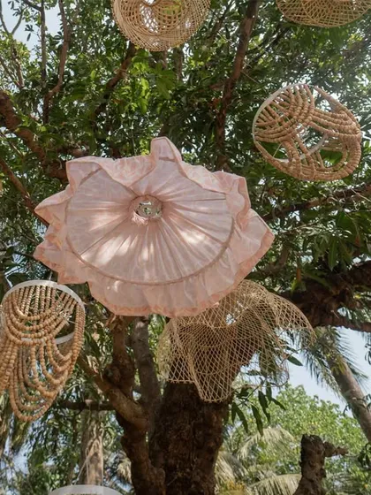 A view looking up into the trees, adorned with an eclectic mix of handcrafted wicker and fabric lanterns.
