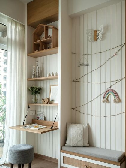 Across from the bed, a foldable study table with an integrated bookshelf was installed. It features a whiteboard surface for creative scribbles, and a small bench offers a cozy spot to sit and relax.