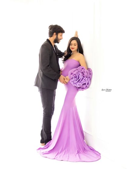 An elegant couple's portrait against a clean white background. The soft lavender gown and the classic black suit create a beautiful and sophisticated contrast.