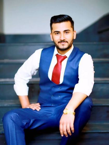 A relaxed and confident portrait of a client seated on the stairs. The blue suit and red tie combination is a classic choice, elevated by professional hair and makeup.