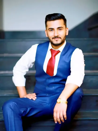A relaxed and confident portrait of a client seated on the stairs. The blue suit and red tie combination is a classic choice, elevated by professional hair and makeup.