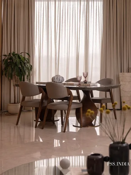 This dining area is bathed in natural light from the large window. The sculptural dining table and modern chairs create an elegant silhouette, perfect for both everyday meals and special occasions.