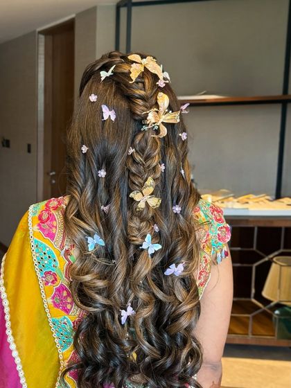 A different angle of the butterfly-adorned half-up style, showing the placement of the clips and the texture of the curls.