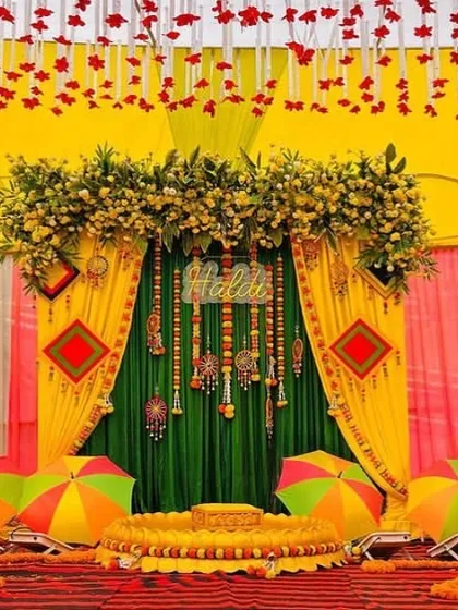 A traditional and colorful Haldi ceremony setup. The combination of yellow and green drapes, marigold flowers, and decorative umbrellas creates a bright and joyous backdrop for the event.