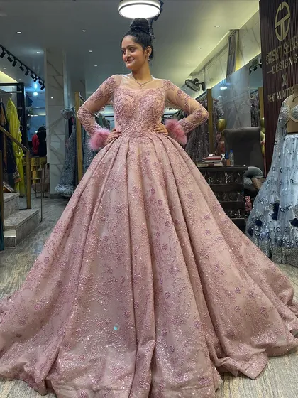 Our model strikes a pose in the dusty pink Cinderella ball gown. This image showcases the gown's beautiful drape and the way the light catches the thousands of sequins woven into the fabric.