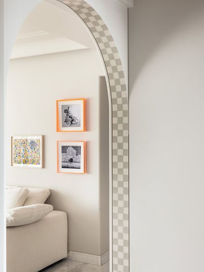 Details matter. The checkered pattern on the archway and the bright orange frames add a playful touch to this corner, reflecting the home's artistic and joyful design.