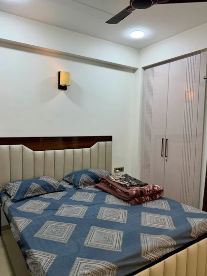 A full view of a bedroom featuring a custom upholstered bed and a matching wardrobe with a subtle grooved pattern on the shutters.