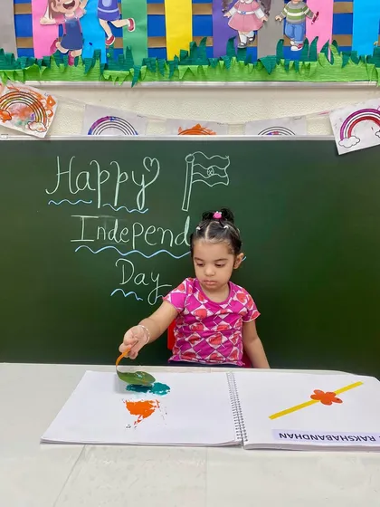 This child is using a leaf to stamp the colours of the flag, a creative technique that combines nature and art to celebrate Independence Day.