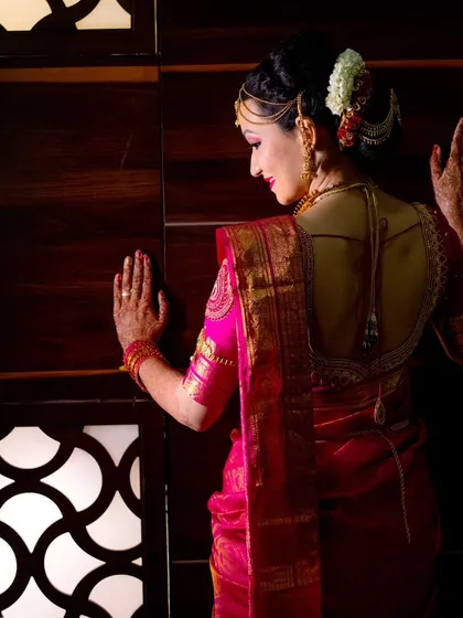 A beautiful back-profile shot of the bride, highlighting the intricate design of her blouse and her elegant hairstyle.