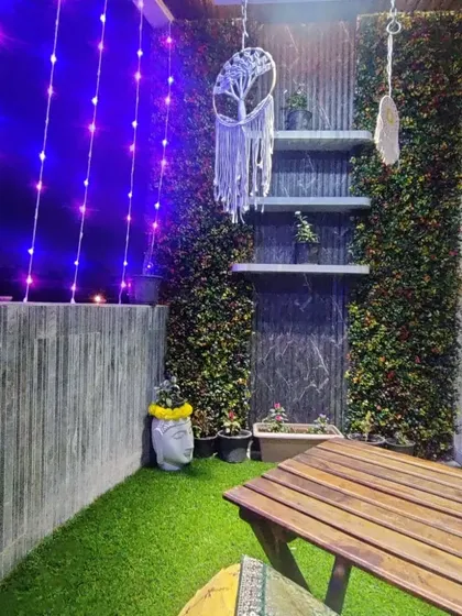 A cozy balcony corner designed for evening relaxation. We combined durable artificial turf, a compact wooden table, and ambient curtain lights to create a magical, low-maintenance outdoor space perfect for unwinding.