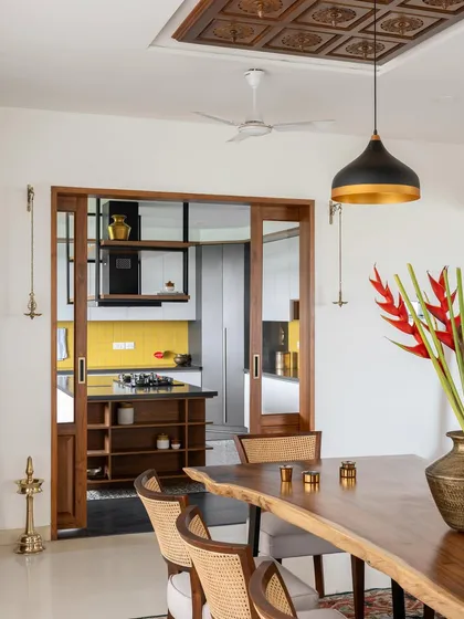 The 'Vasudhalayah' kitchen is defined by elegant wood and glass sliding doors, allowing it to be either open to the dining area or privately enclosed.