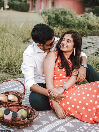 A sweet and romantic moment during a picnic-themed pre-wedding shoot. The natural green setting and their loving gaze create a perfect picture of contentment.
