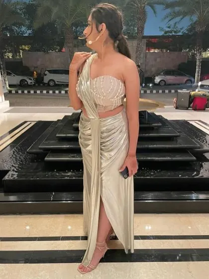 A side profile of the sister of the bride in her custom-made metallic saree for the cocktail party. The one-shoulder pearl-embellished blouse adds a touch of glamour.