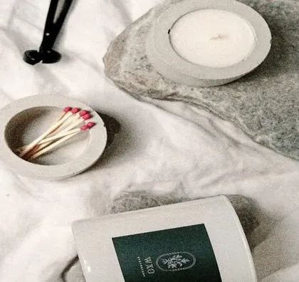 This image shows how we can create a lifestyle product photography setup anywhere. Here, we've styled scented candles and home decor items on a simple fabric background for a cozy, authentic feel.
