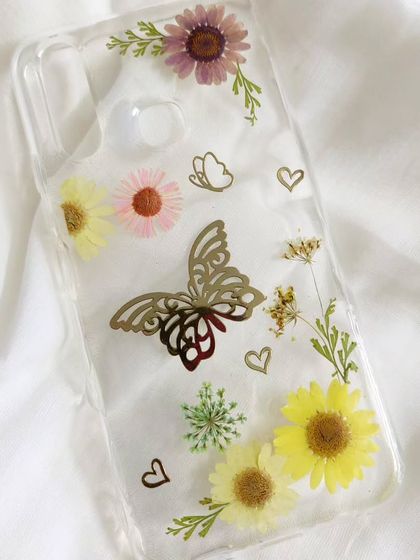 This resin phone case is extra special, with a delicate butterfly charm embedded among the pressed flowers. It's a perfect example of how we can personalize your accessories.