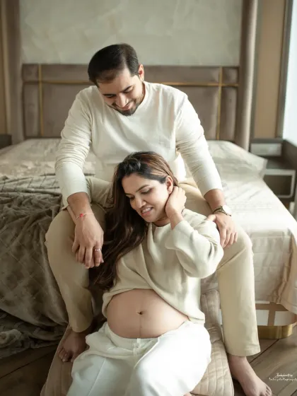 A candid shot of the couple sharing a laugh in a relaxed home environment. These unposed moments often become the most cherished memories from a maternity photoshoot.