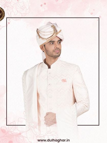 A groom in a white sherwani with a pink safa and stole, offering a soft and romantic color combination for a wedding.