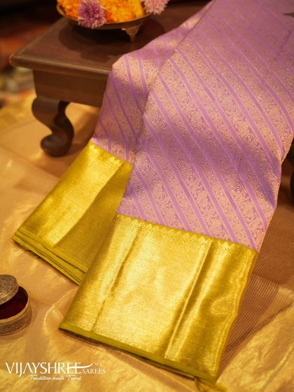 A beautiful lavender Kanjivaram with diagonal zari stripes and a solid gold border, a modern yet traditional piece.