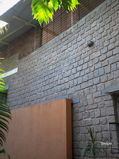 The curved stone wall of the Rehmat Tarikere Residence, seen from the garden. This feature was designed to buffer the home from the southern sun while creating a beautiful, textured facade.