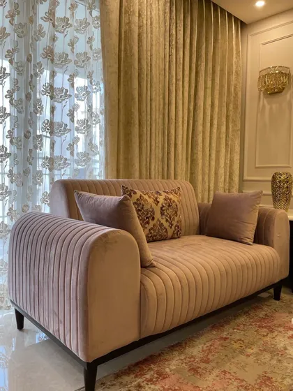 This dusty rose two-seater sofa with vertical channel tufting is a perfect example of how pastel colors can create a space that feels calm, relaxed, and luxe. It’s set against a wall with classic moulding details.