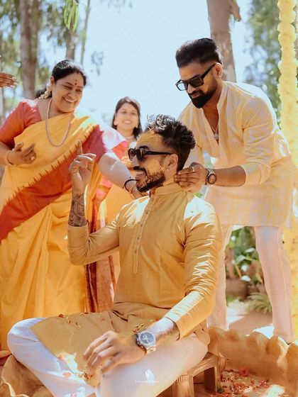 A candid moment during the groom's Haldi ceremony, as his friends and family playfully apply turmeric paste.